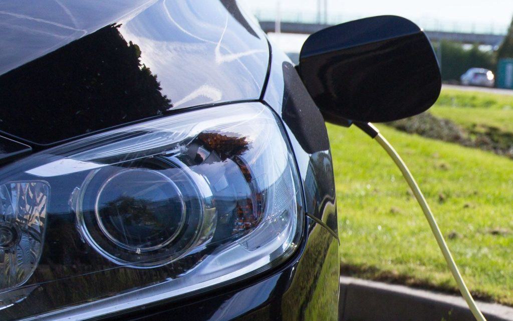 een deel van de achterkant van een elektrische auto, waaruit een oplaadsnoer hangt