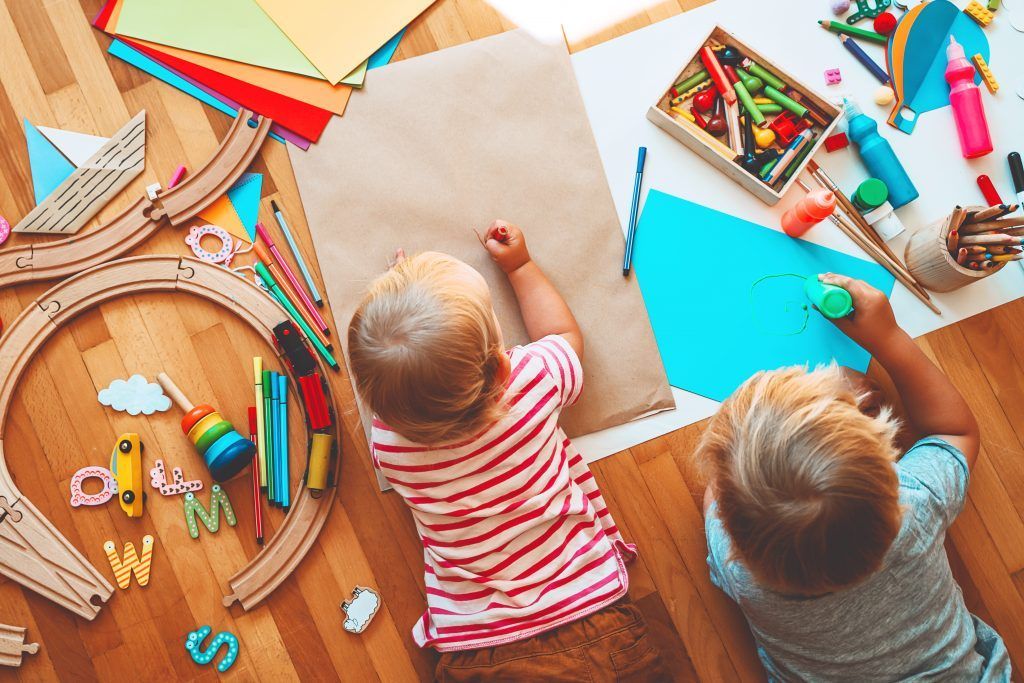 twee peuters tekenen en spelen op de grond