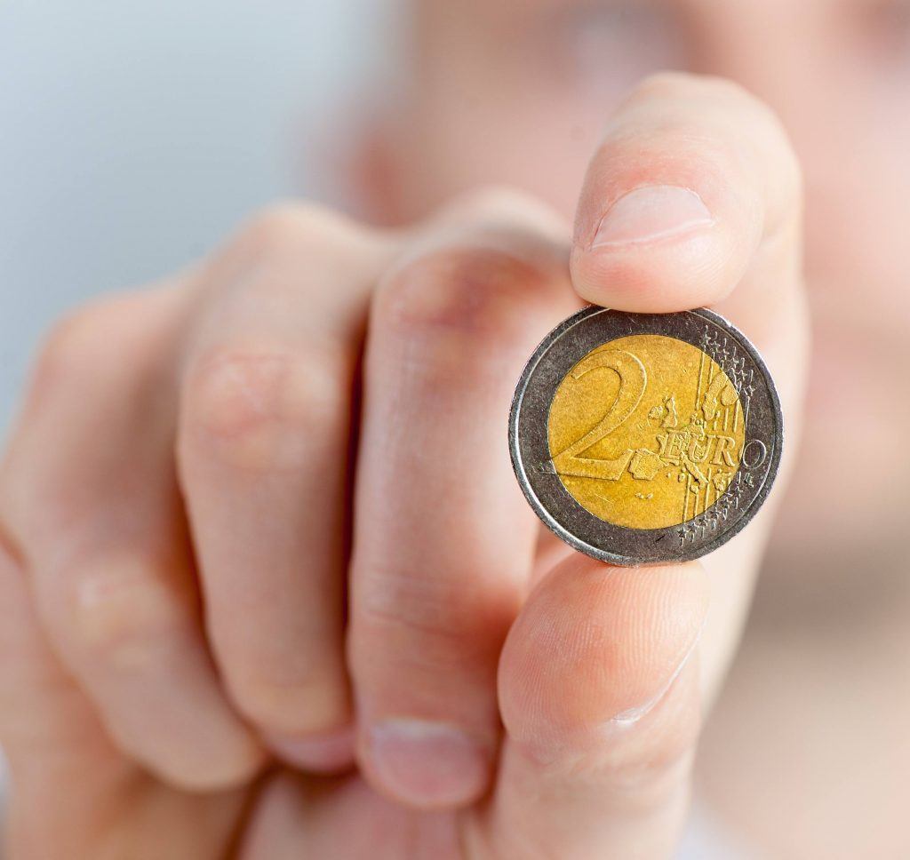 Een twee euromunt wordt vastgehouden in een hand