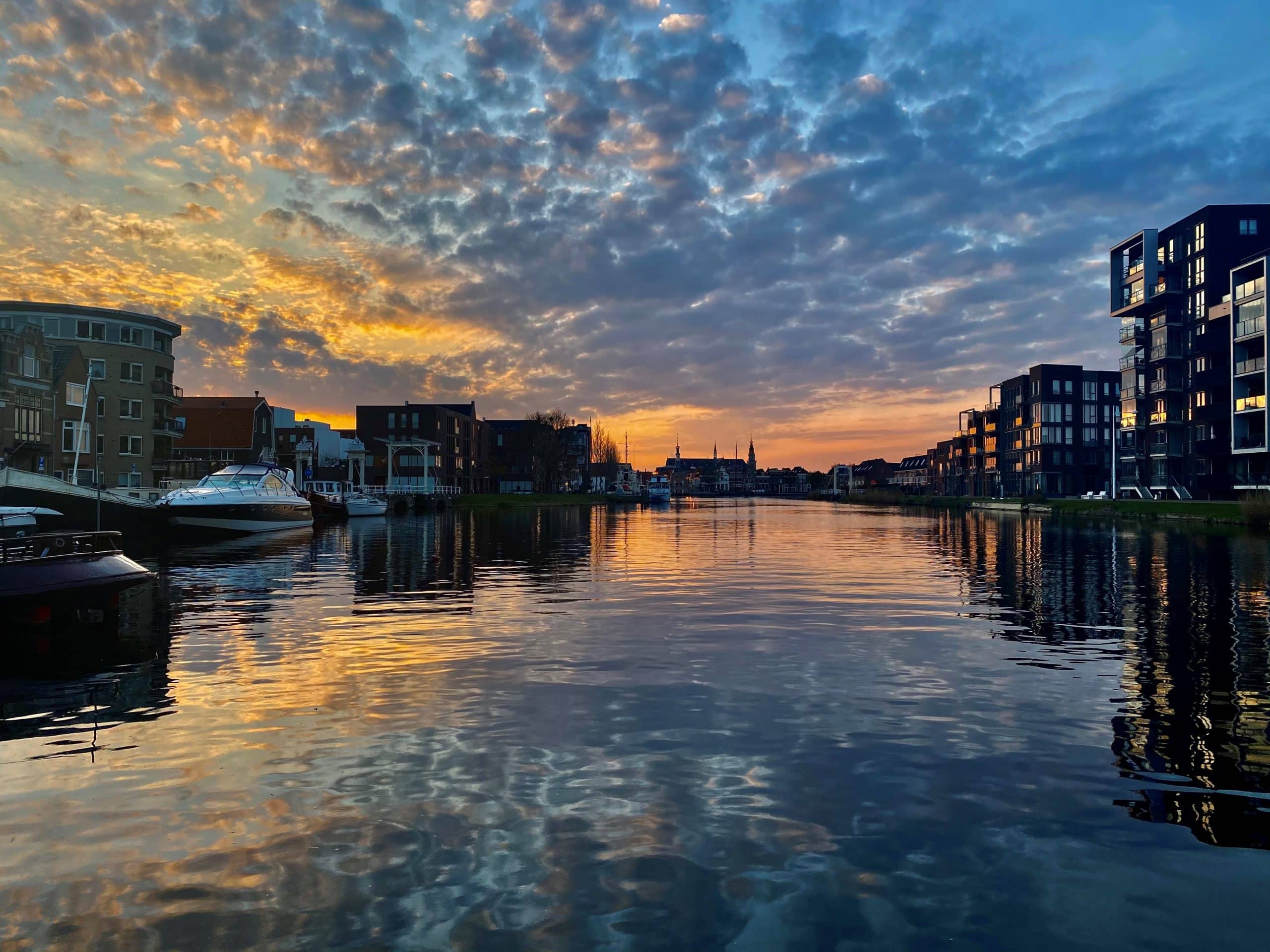 Huizen aan het water, blauw oranje lucht met weerspiegeling in het water