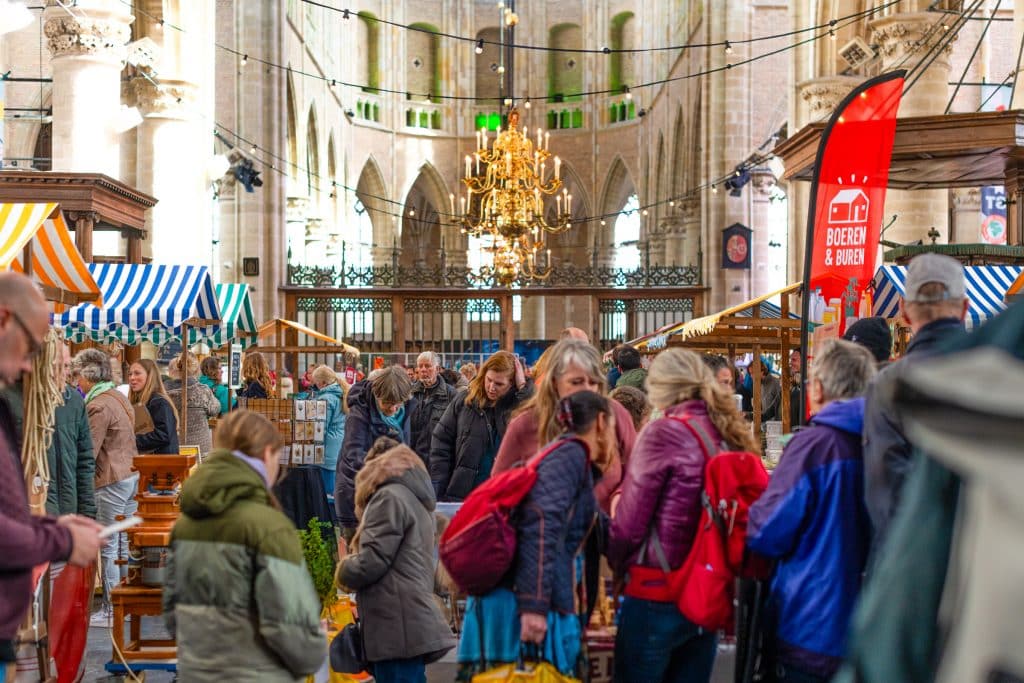 Drukke markt vol met mensen tijdens UPfest in de Grote Kerk Alkmaar