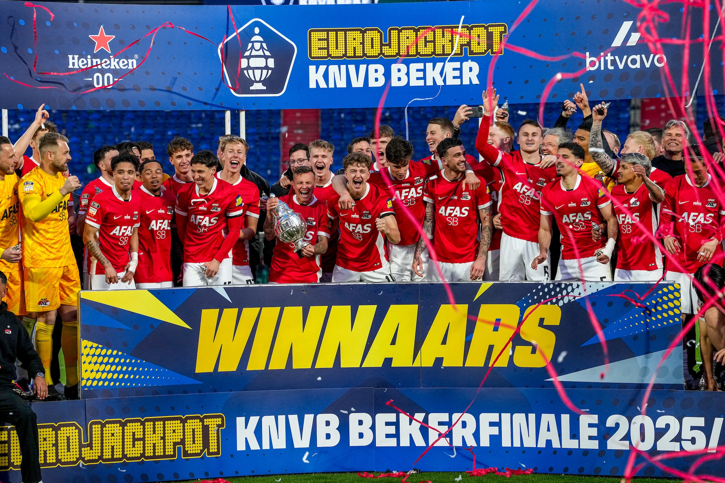 Een groep voetballers van AZ staat op een podium en houdt de KNVB Beker in de lucht