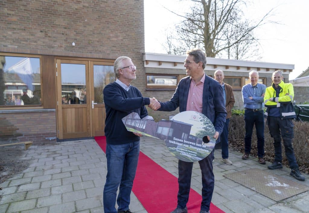 Overhandiging van grote kartonnen sleutel van de gemeente aan de stichting dorpshuis.