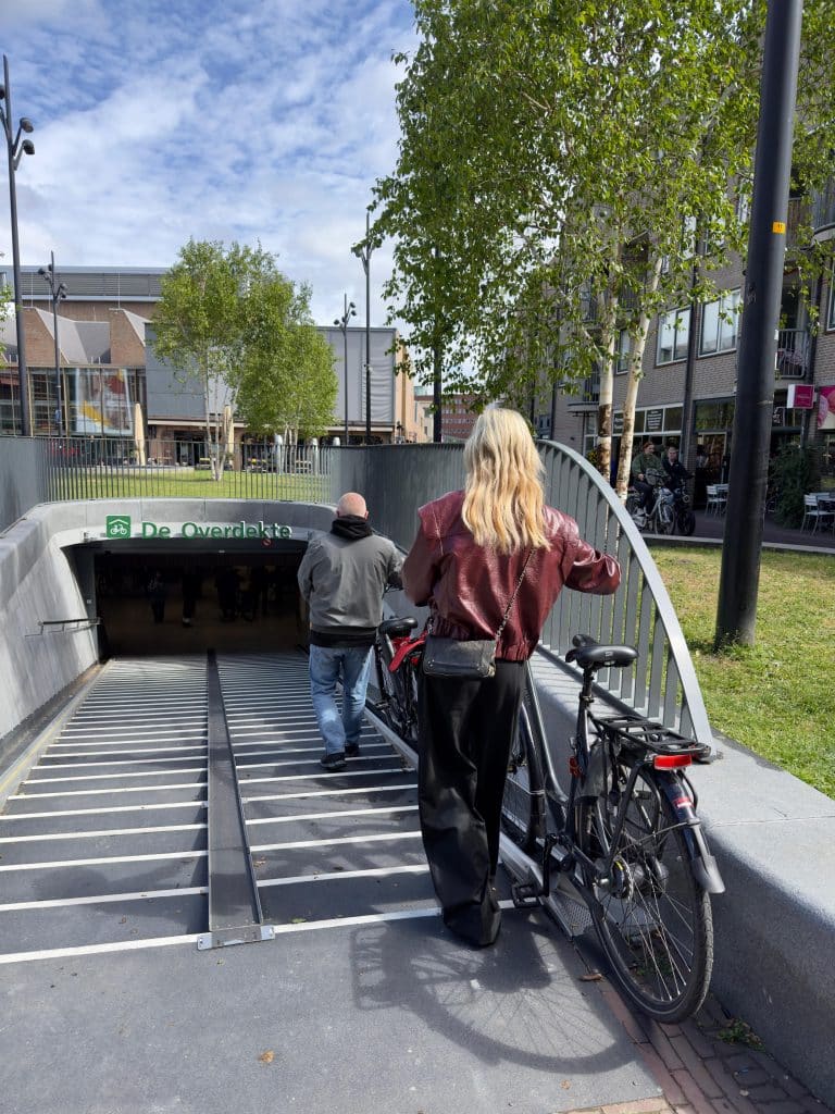 2 mensen lopen met de fiets de fietsenstalling De Overdekte in