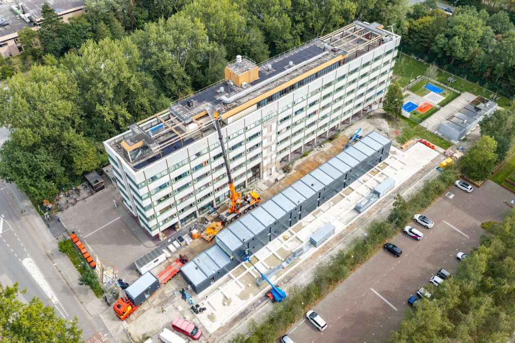 Luchtfoto van de Robonsbosweg met de tijdelijke woonunits naast het bestaande gebouw.