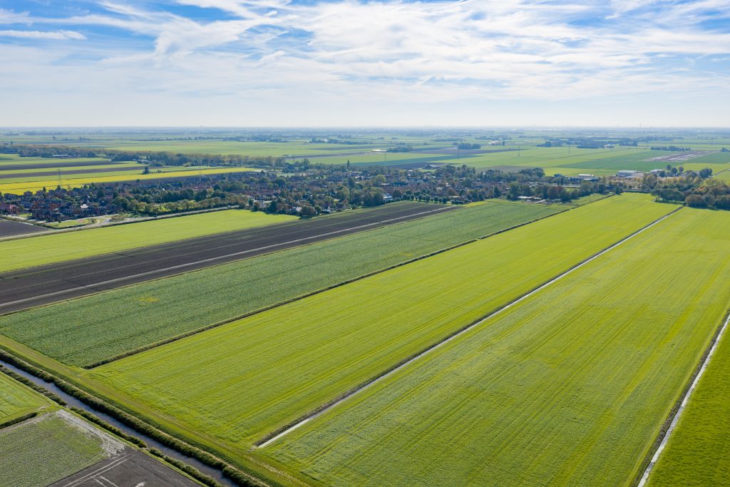 Luchtfoto van Stompetoren met uitgestrekte groene weilanden, akkers en sloten rondom het dorp.