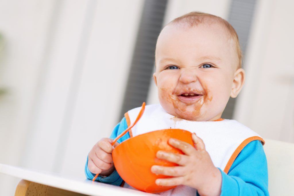 baby eet groente uit oranje kome