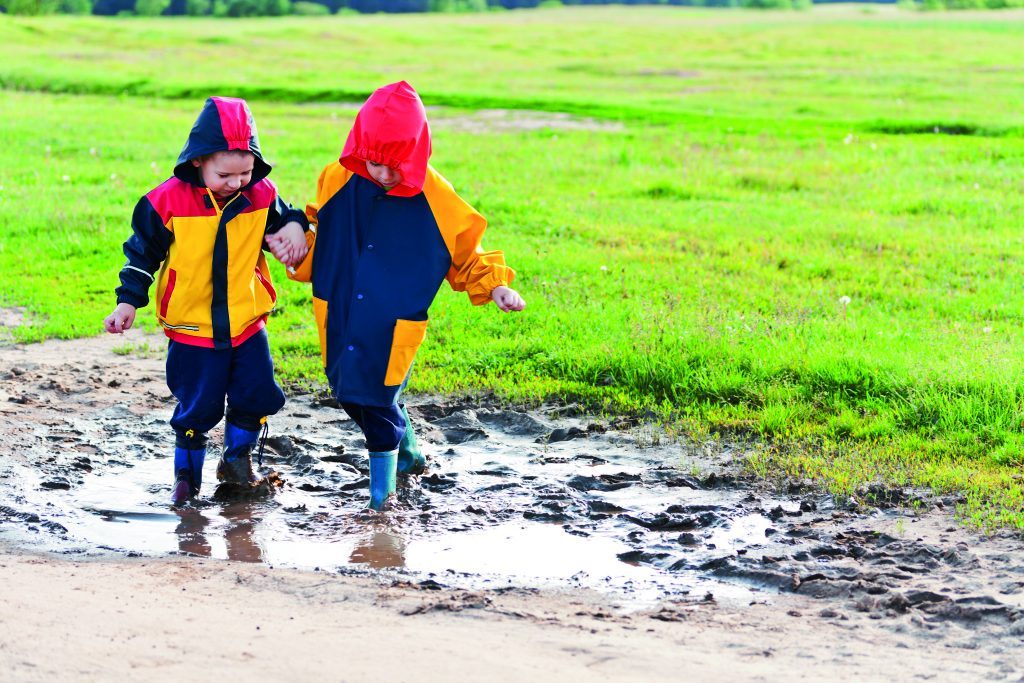 twee kinderen buiten op een grasveld in een plas