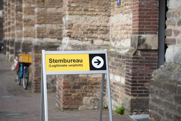 buitenbord op poten waarop wordt aangegeven dat het stembureau rechts, in het gebouw ernaast, is