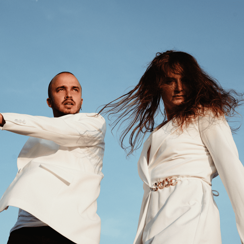 twee personen dansen met elkaar. Ze dragen witte kleding