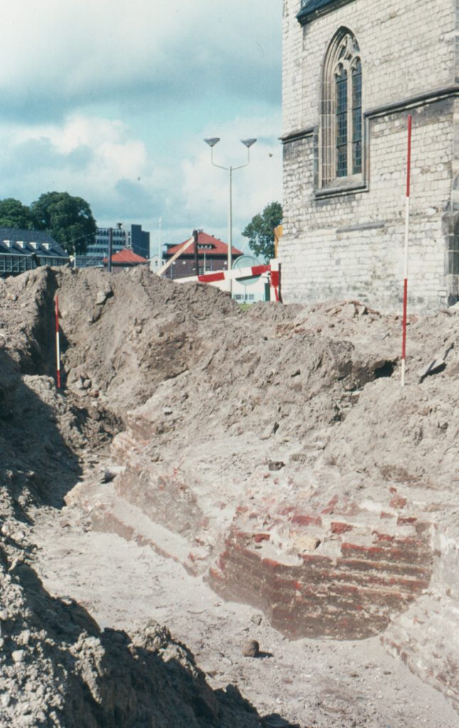 Foto van het onderzoek van de oostelijke twee funderingsblokken door de Rijksdienst Oudheidkundig Bodemonderzoek en E.H.P. Cordfunke in 1970, na de sloop van het R.O.G.-gebouw en voor de aanleg van de Bagijnenstraat (foto E.H.P Cordfunke).
