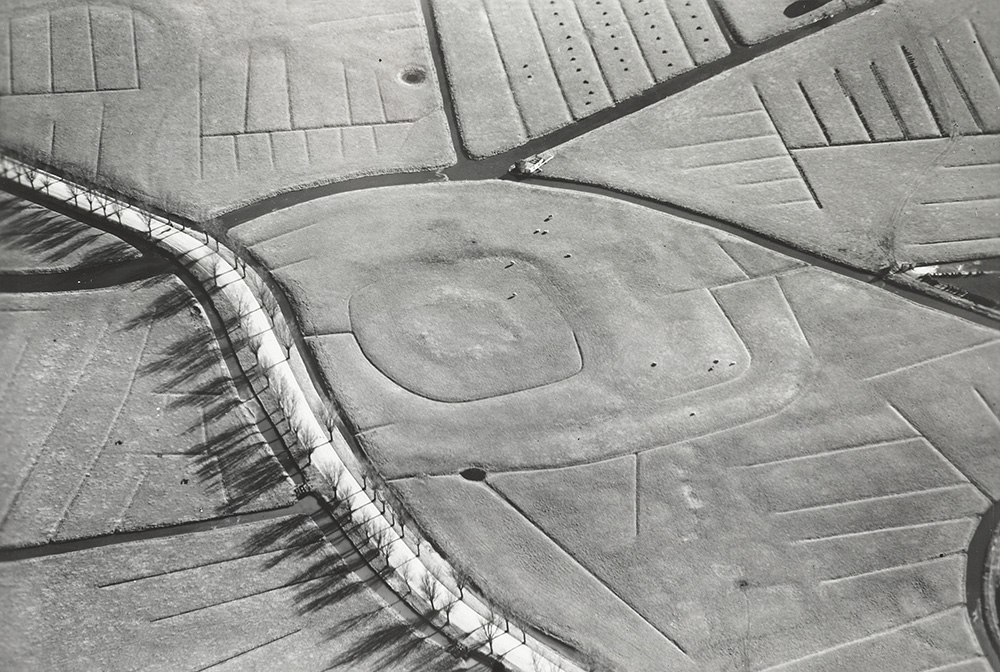 Luchtfoto uit de periode 1920-1940 met heel duidelijk de contouren van kasteel de Middelburg. Te zien is dat het kasteel meerdere omwallingen en grachten heeft gehad. Ook is heel mooi de contour van de slinger van het oude verloop van de Munnikenweg te zien in het weiland. Opvallend is dat deze kromming vanaf de weg weer richting het kasteel gaat