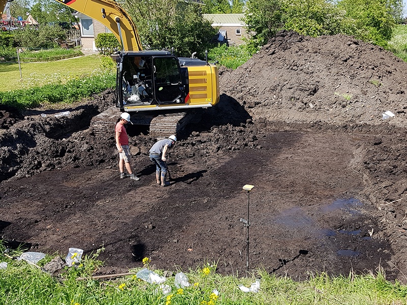 Opgraving van de ondergrond onder de middeleeuwse kleilaag: in de donkerbruine veengrond tekenen zich de met grijze klei gedempte sleuven van de veenstekers af