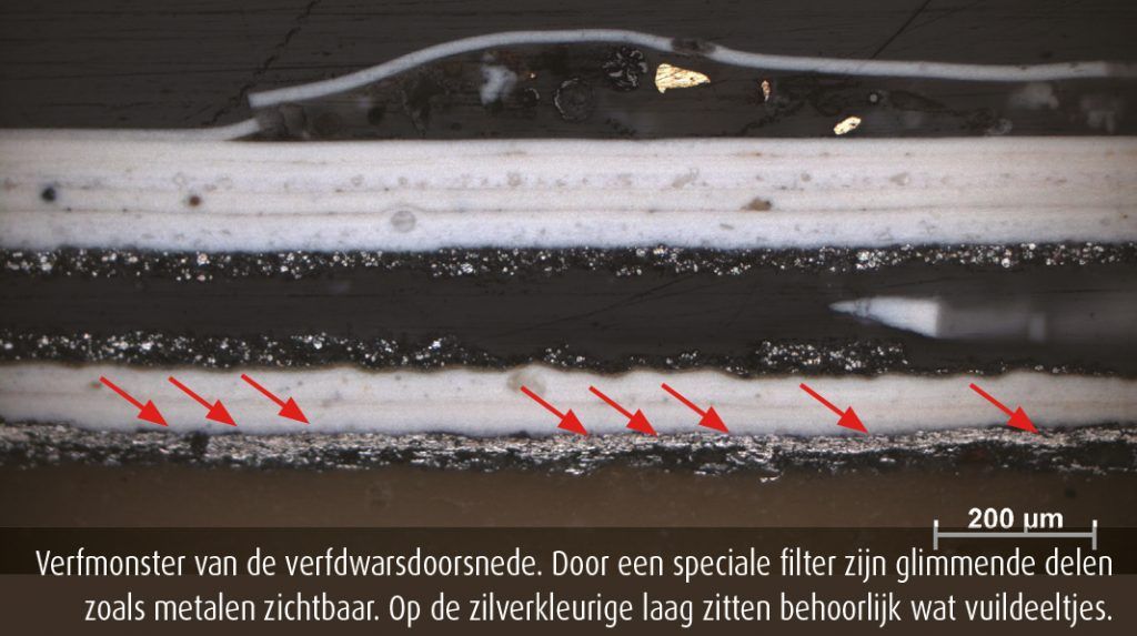 Verfmonster van de verfdwarsdoorsnede. Door een speciale filter zijn glimmende delen zoals metalen zichtbaar. Op de zilverkleurige laag zitten behoorlijk wat vuildeeltjes.