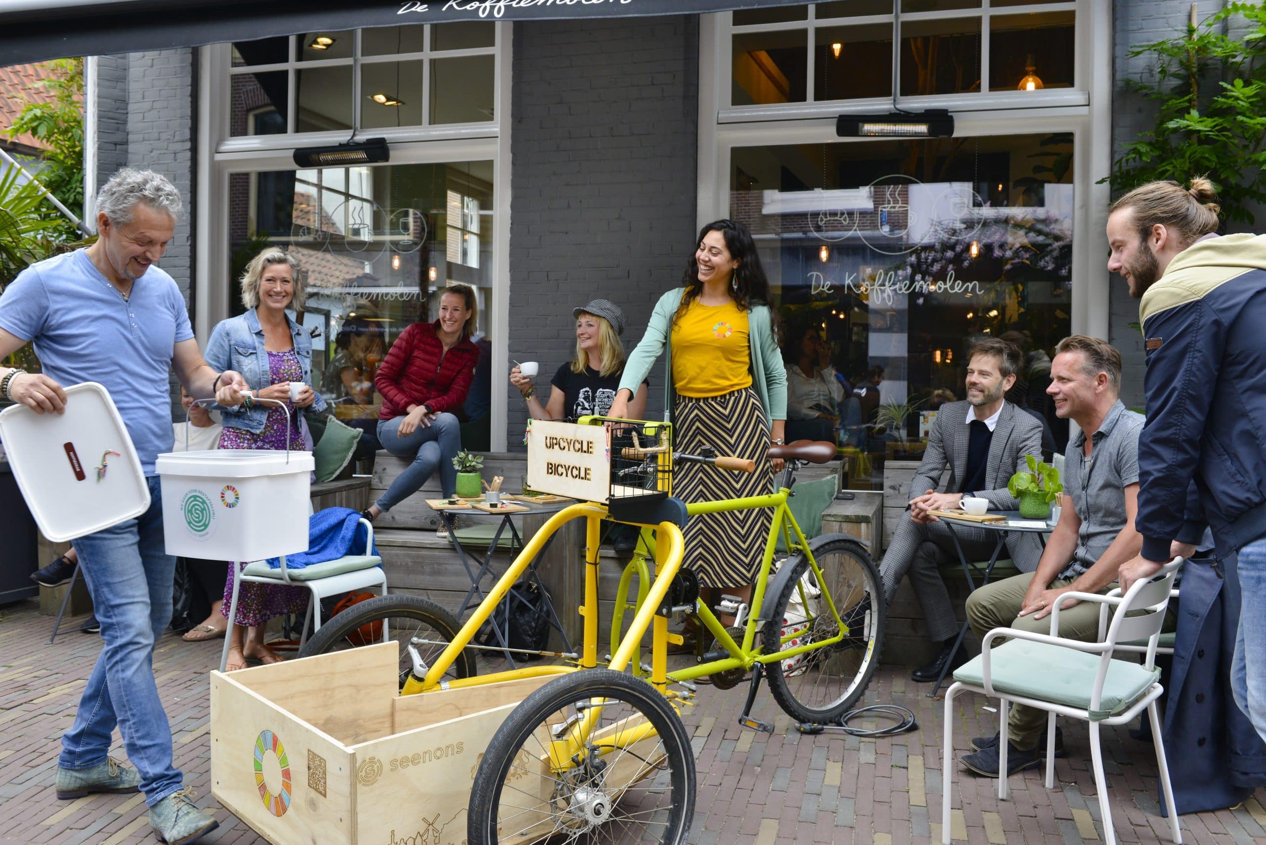 Mensen op het terras bij de Koffiemolen waar ook de upcycle bicycle staan.
