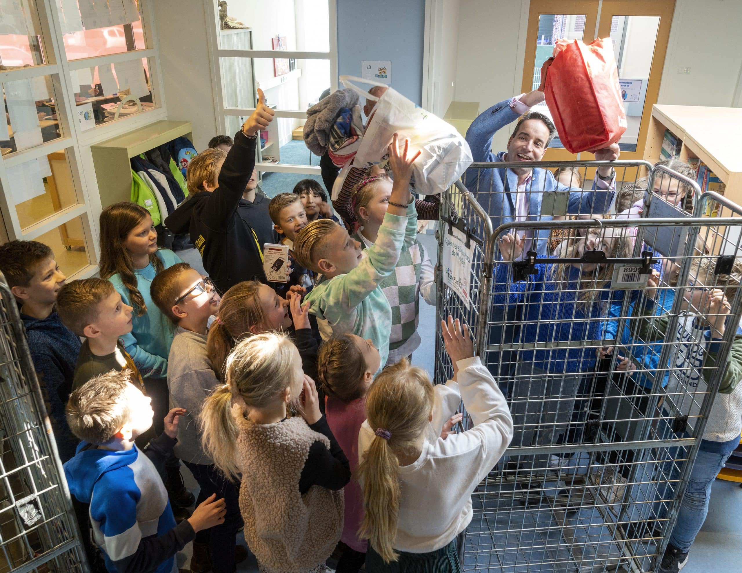 Kinderen gooien een tas met oud textiel in een verzamelkar