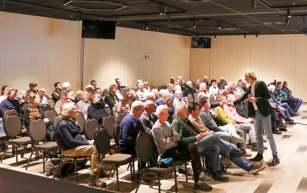 man geeft deelnemers aan een presentatie het woord met microfoon