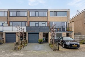 Huizen van drie verdiepingen met een garage beneden in de woning met een pad ervoor.