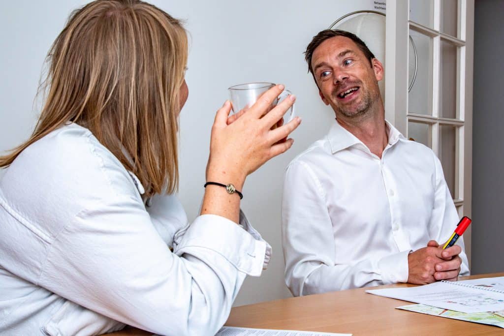 2 mensen in gesprek aan tafel.